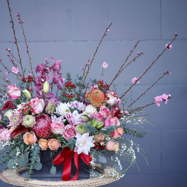 Large floral arrangement with pink, white, and peach blooms in a black container