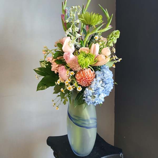 Mixed pastel bouquet in a tall frosted glass vase