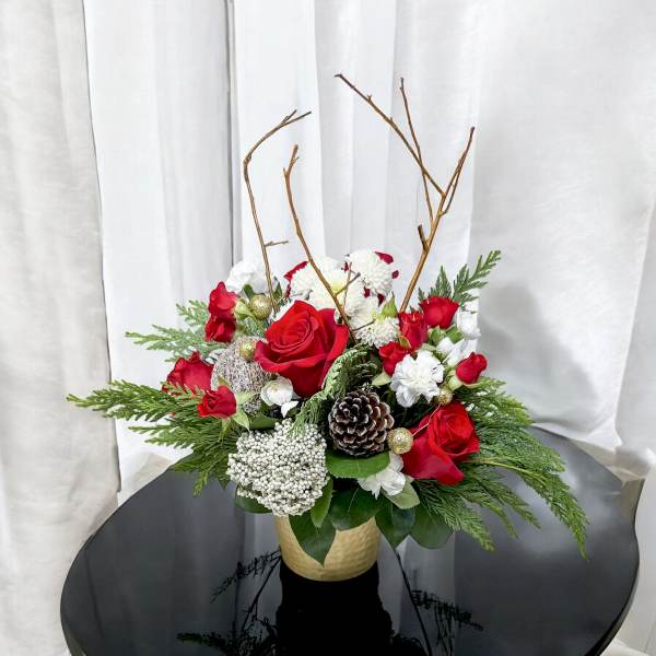 Red roses and white flowers in a gold vase with pinecones and branches