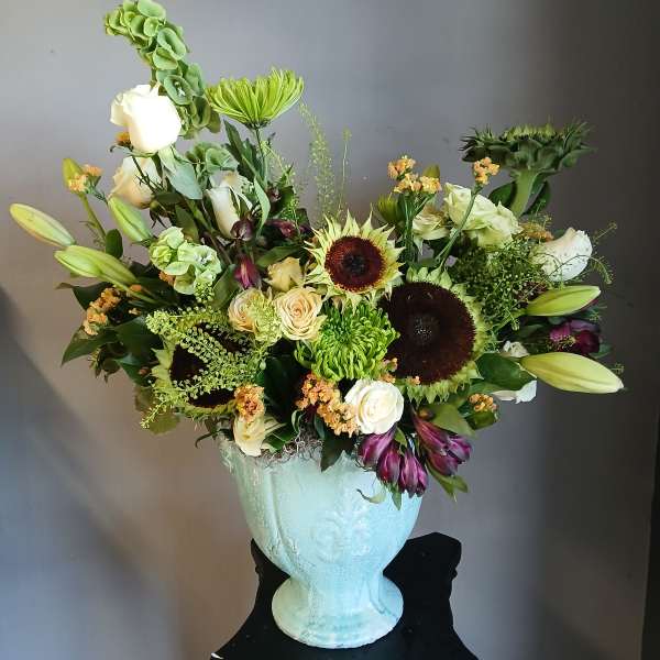 Large mixed flower arrangement in a pale blue vase