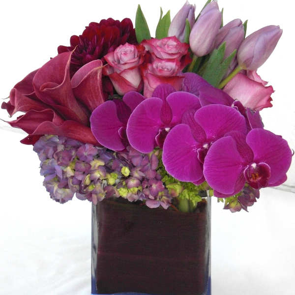 Pink and purple floral arrangement in a square glass vase