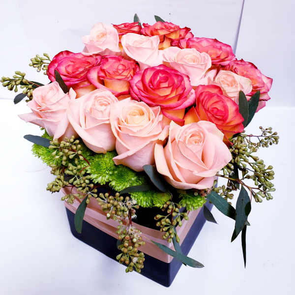 Pink and coral roses arranged in a square gift box