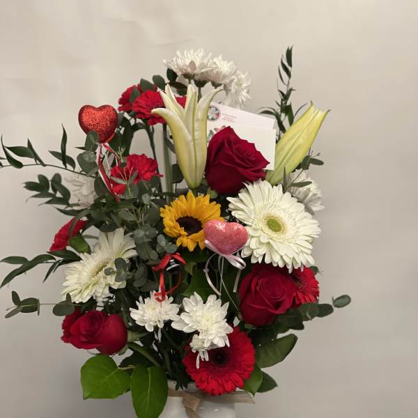 Mixed bouquet of red roses, white lilies, and daisies in a white vase