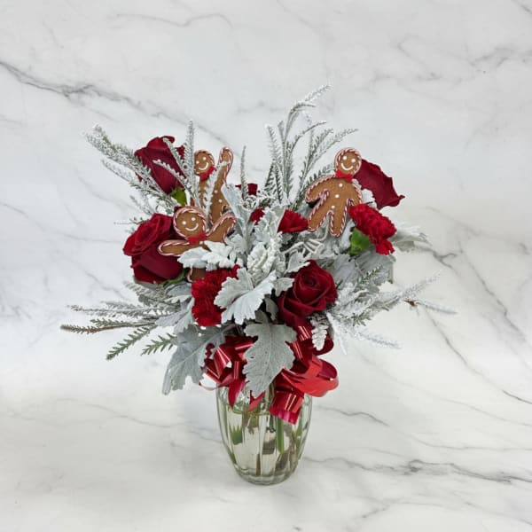Red roses and carnations in a glass vase with gingerbread ornaments