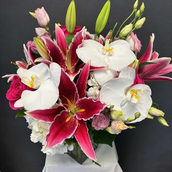 Bouquet of pink and white lilies and orchids in a glass vase