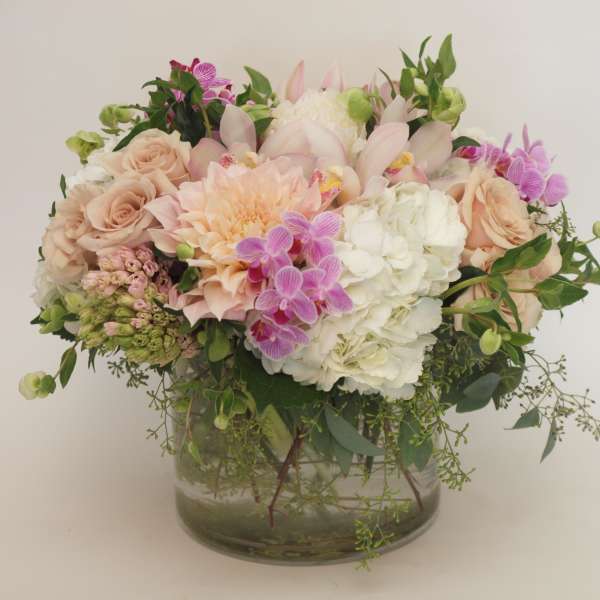 Pastel bouquet of roses, hydrangeas, orchids, and dahlias in a glass vase
