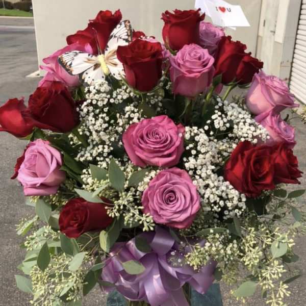 Bouquet of red and pink roses in a glass vase with a purple ribbon