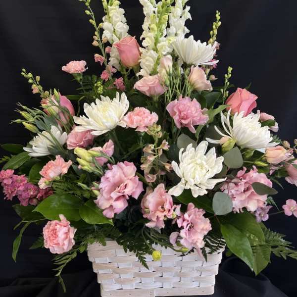 Pink and white mixed flower arrangement in a white basket