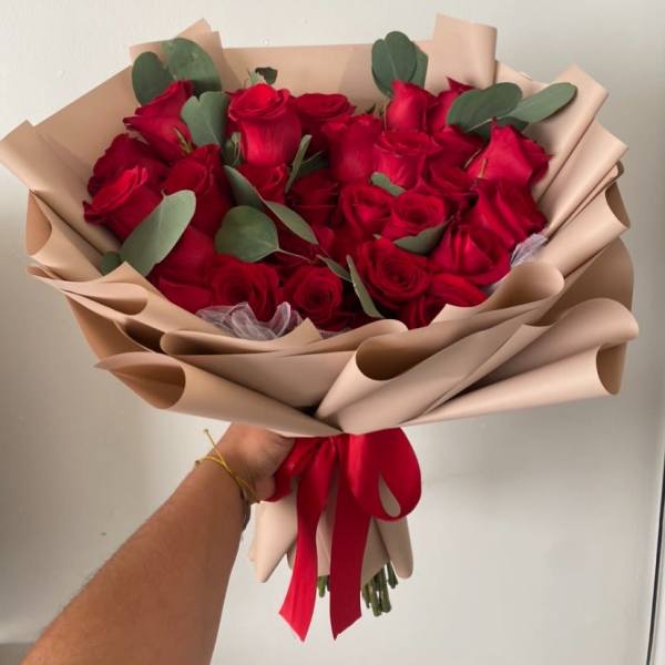 Bouquet of red roses wrapped in beige paper with a red ribbon