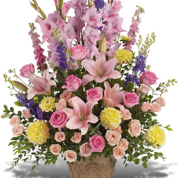 Tall mixed flower arrangement in a decorative urn with pink lilies and roses
