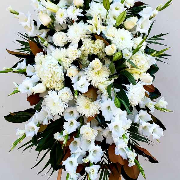 Large white funeral spray with lilies, roses, and chrysanthemums on an easel