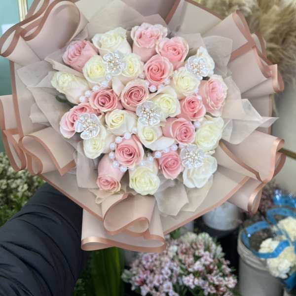 Bouquet of pink and white roses wrapped in blush paper