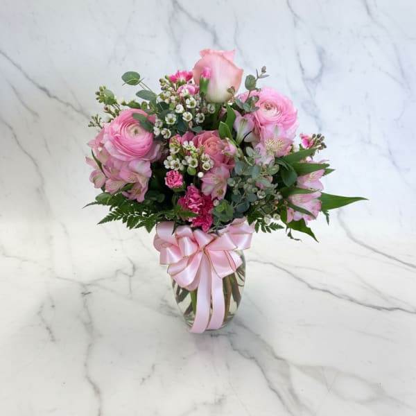 Pink mixed flower bouquet in a glass vase with a ribbon