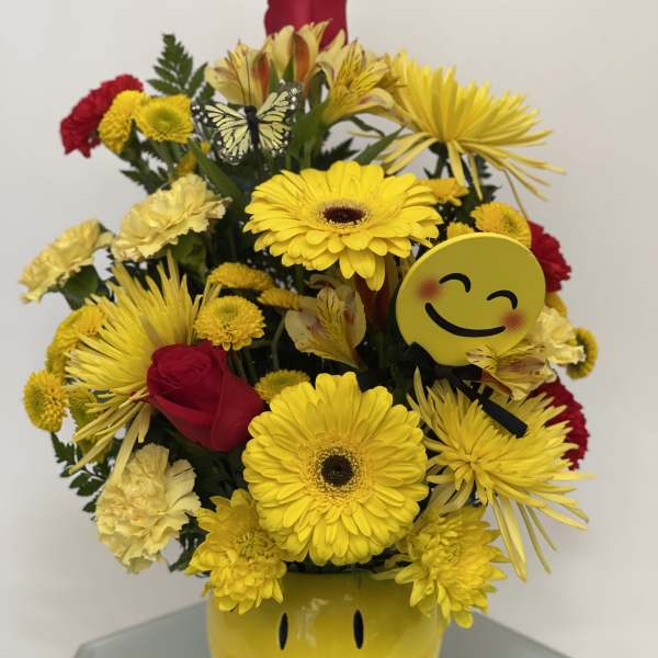 Yellow and red mixed bouquet in a smiley-face vase with emoji accents