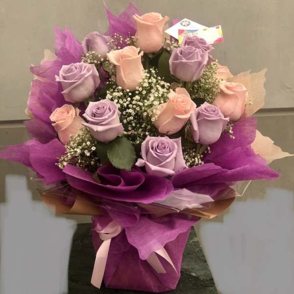 Bouquet of lavender and peach roses wrapped in purple paper