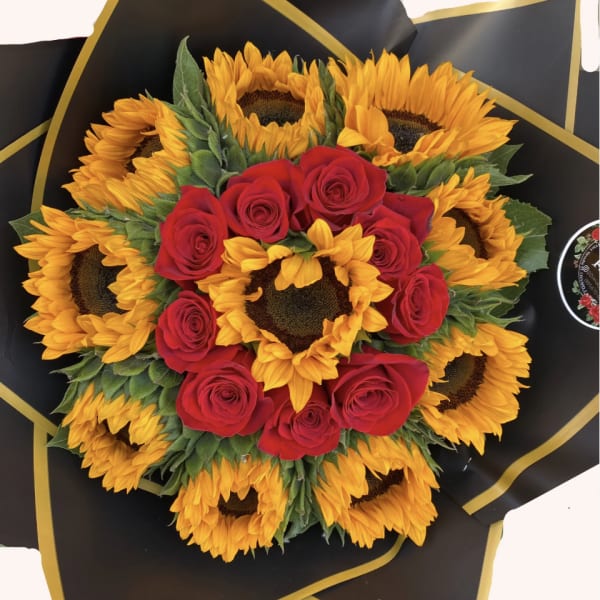 Bouquet of red roses and sunflowers wrapped in black paper with gold trim