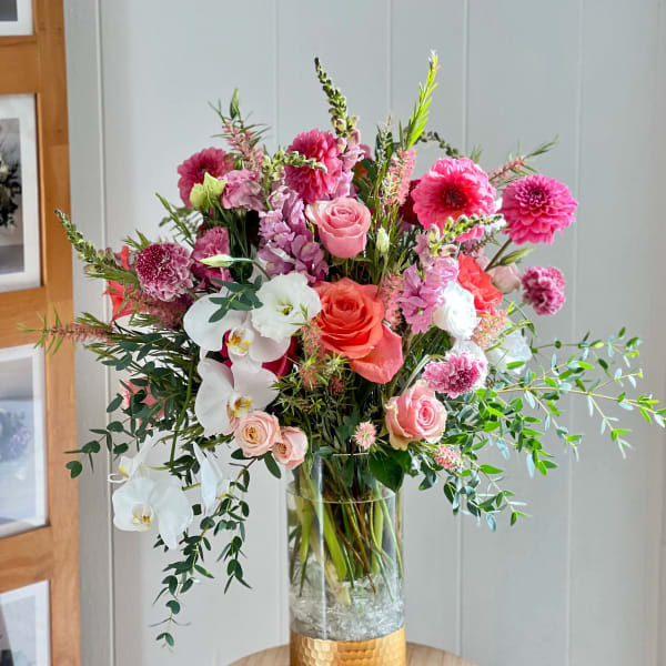 Tall mixed bouquet of pink, white, and coral flowers in a glass vase