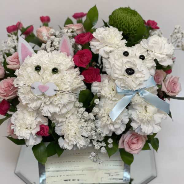 Bouquet of white and pink flowers arranged as two bunny faces in a mirrored box