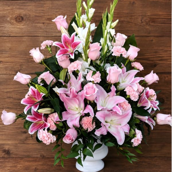 Pink lilies and roses arranged in a white vase