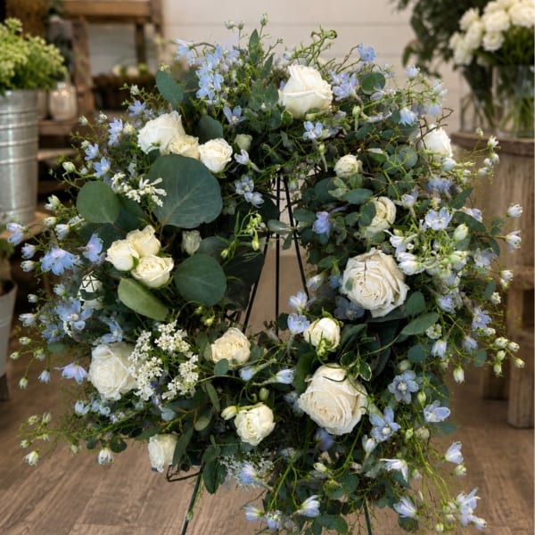 White roses and pale blue flowers arranged on a metal stand