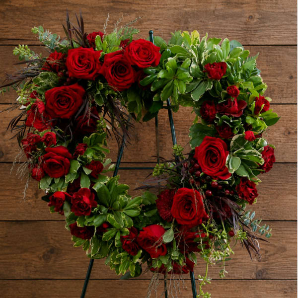 Heart-shaped wreath of red roses and greenery on a stand