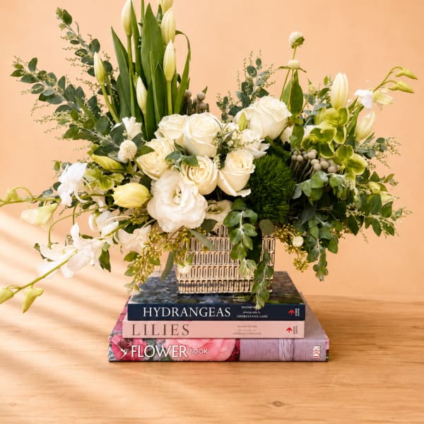 White roses and lilies arranged in a square vase with greenery