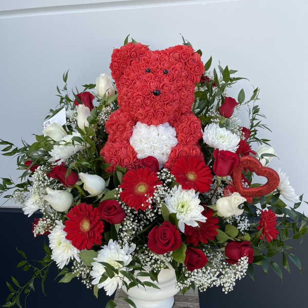 Heart-shaped teddy bear made of red roses in a mixed floral arrangement