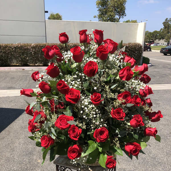 Large arrangement of red roses with baby's breath on a stand