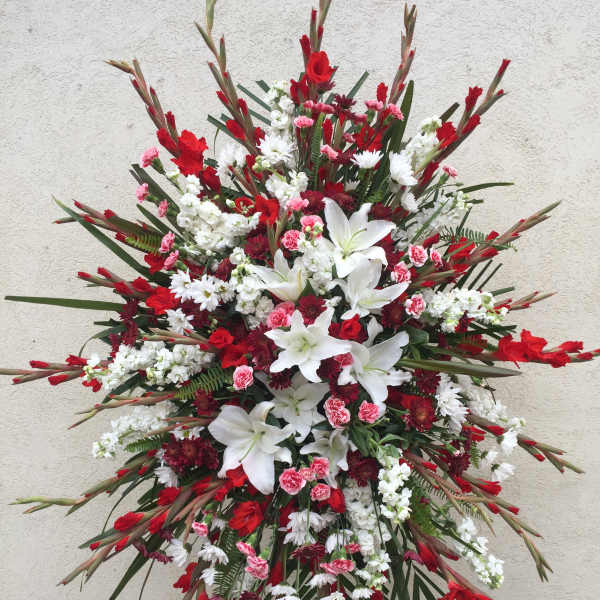 Large red, white, and pink funeral spray with lilies and daisies