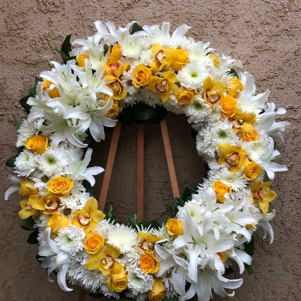 Yellow and white floral wreath on a stand