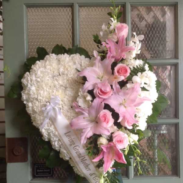 Heart-shaped funeral wreath with pink lilies, roses, and white flowers