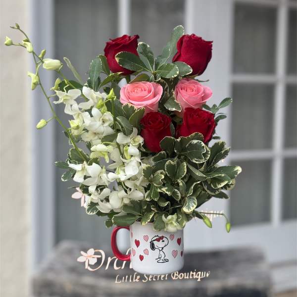 Bouquet of red and pink roses with white flowers in a Snoopy mug