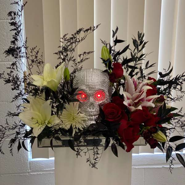 Floral arrangement with red and white flowers around a silver skull centerpiece