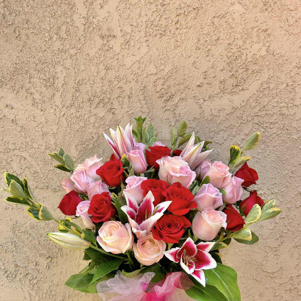 Bouquet of red and pink roses with lilies in a glass vase