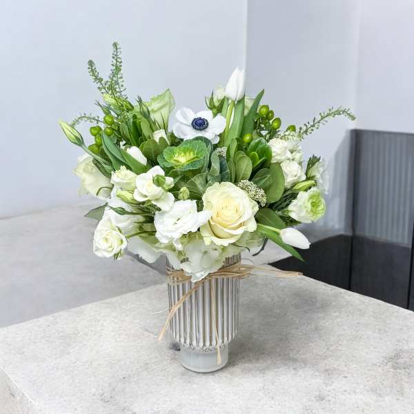 White and green floral arrangement in a striped glass vase