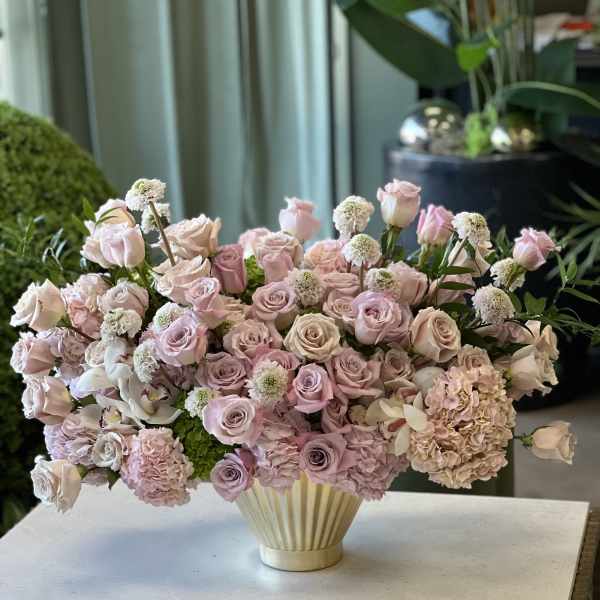 Pink and blush roses with hydrangeas in a cream vase
