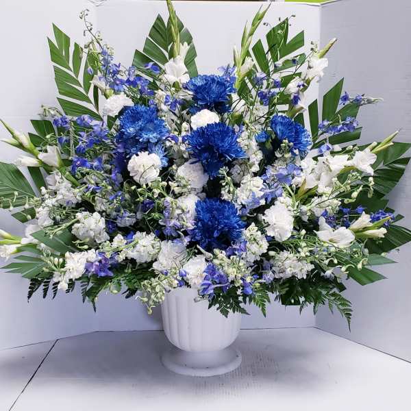 Blue and white floral arrangement in a white pedestal vase