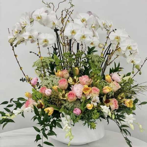 Large floral arrangement with white orchids and pink roses in a white vase