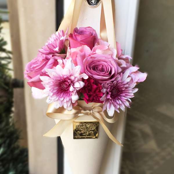 Pink rose and chrysanthemum bouquet wrapped in cream paper with ribbon