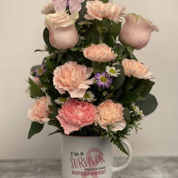 Pink and peach floral arrangement in a mug with a survivor message