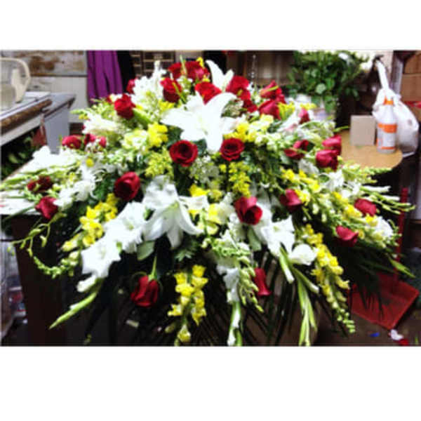 Large floral spray with red roses, white lilies, and yellow flowers