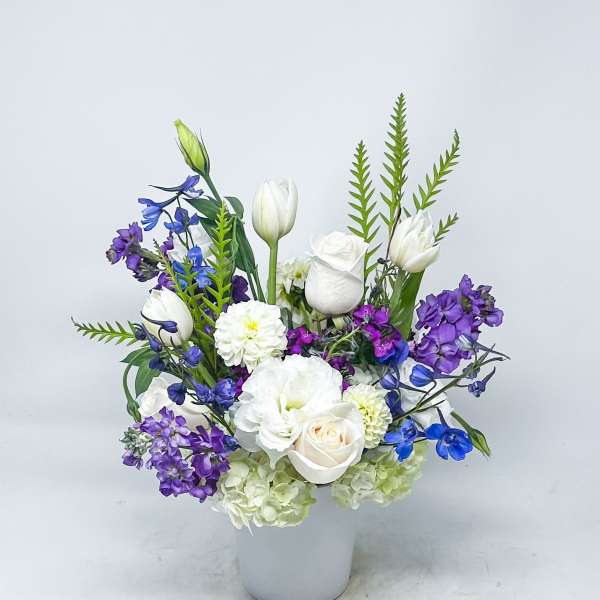 White and purple floral arrangement in a white vase