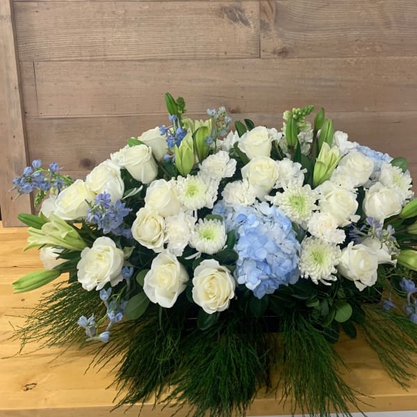 Low floral arrangement of white roses, lilies, and blue hydrangea