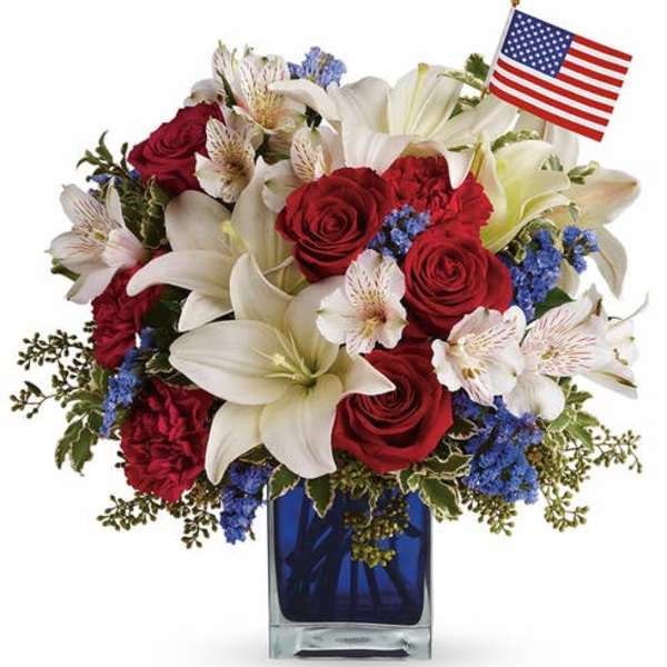Red roses and white lilies in a blue vase with a small American flag