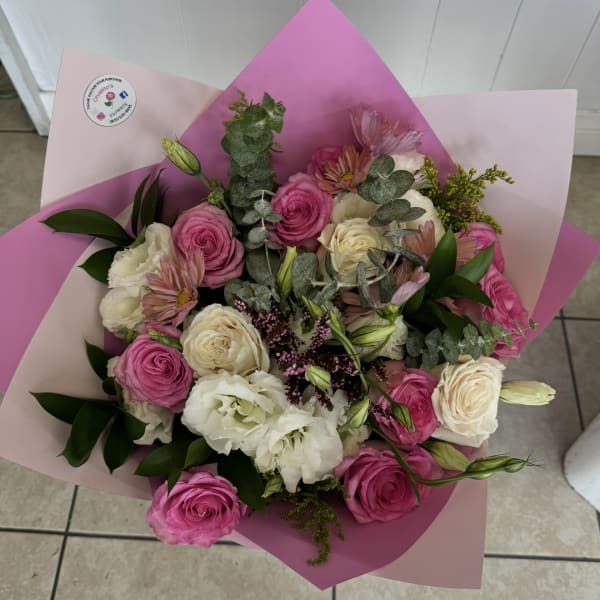 Bouquet of pink and white roses with pale blooms wrapped in pink paper