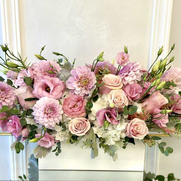 Pink and white floral arrangement with roses and dahlias in a white container
