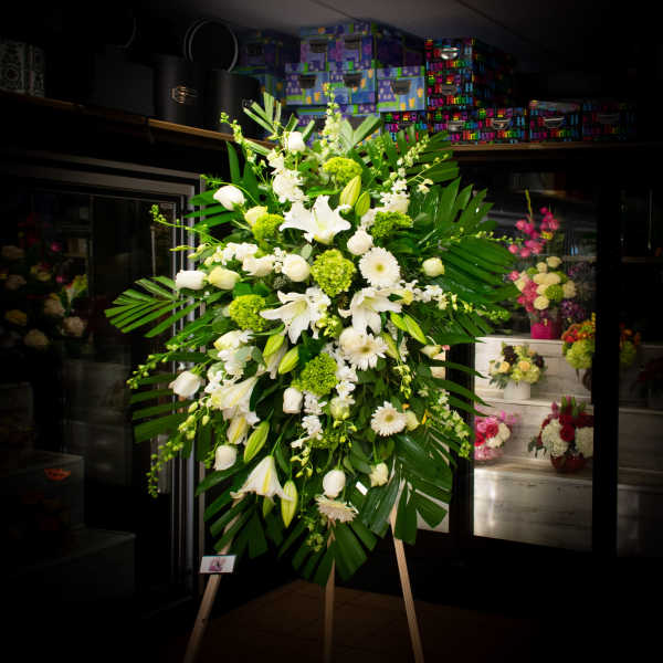 Large white and green standing floral spray on an easel