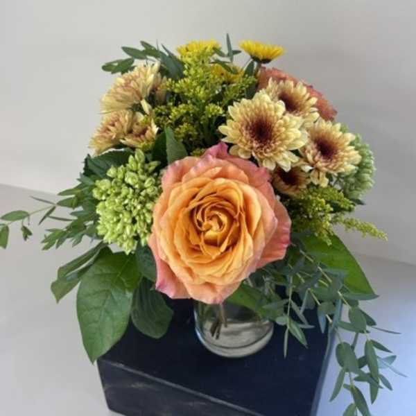 Peach rose bouquet with yellow chrysanthemums in a glass vase