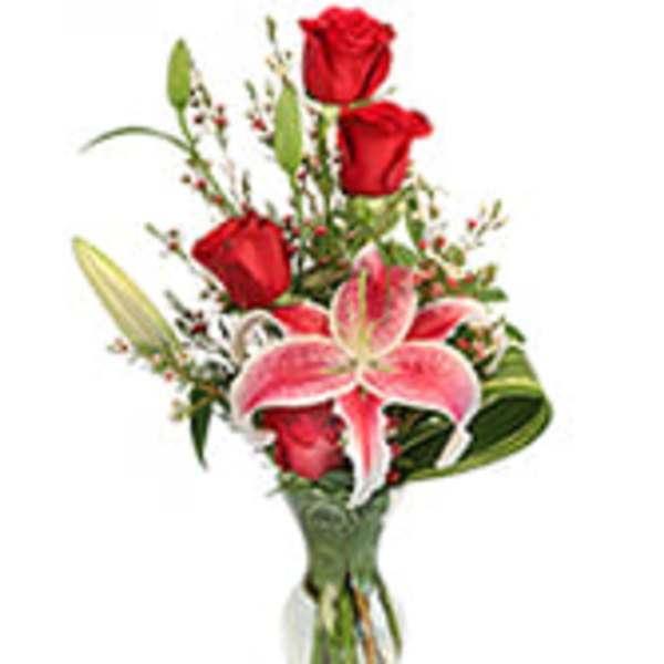 Bouquet of red roses and a pink lily in a clear glass vase