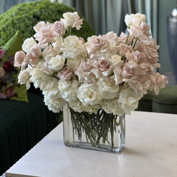 Blush and white roses arranged in a clear rectangular vase